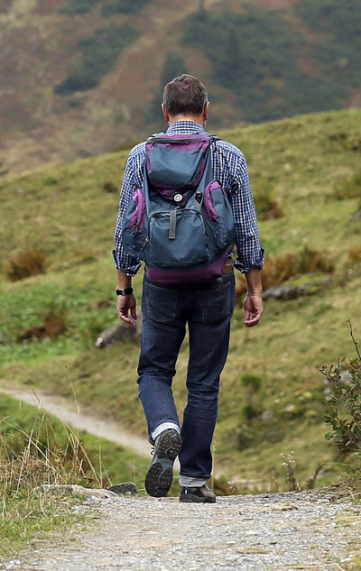 A sole hiker A sole hiker walking down an open trail.